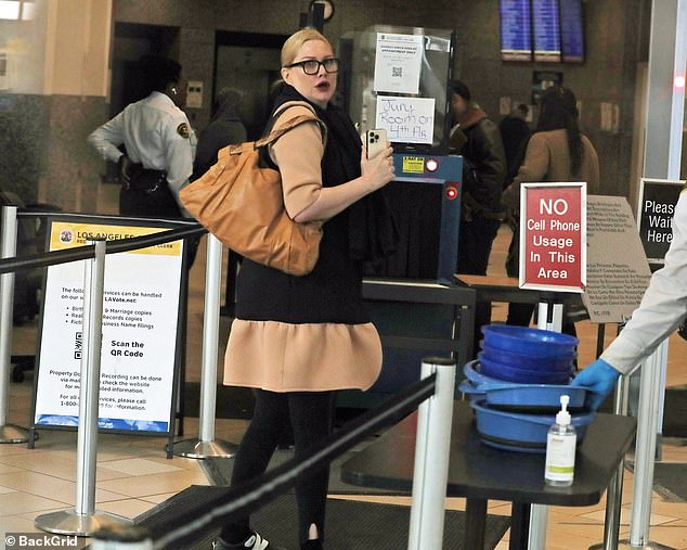 Evans appeared open-mouthed as she passed through security, still using a cell phone despite a sign telling her not to do so
